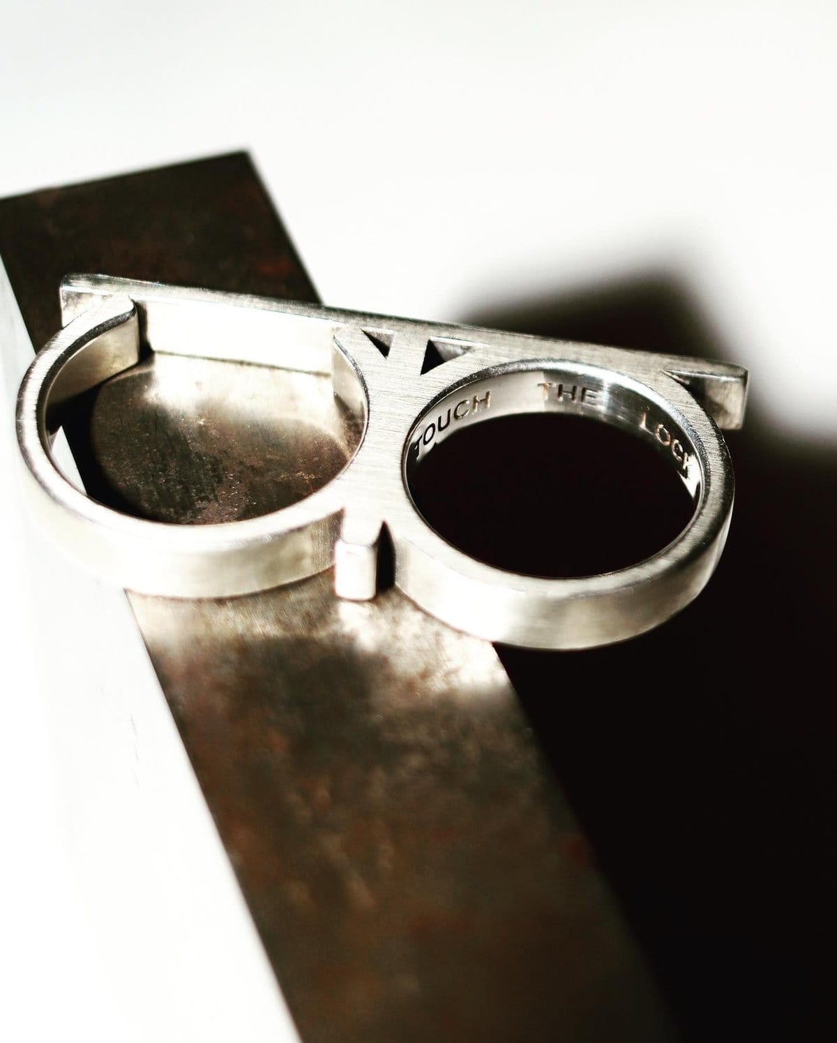 Bague double doigt en argent posée sur une barre de métal