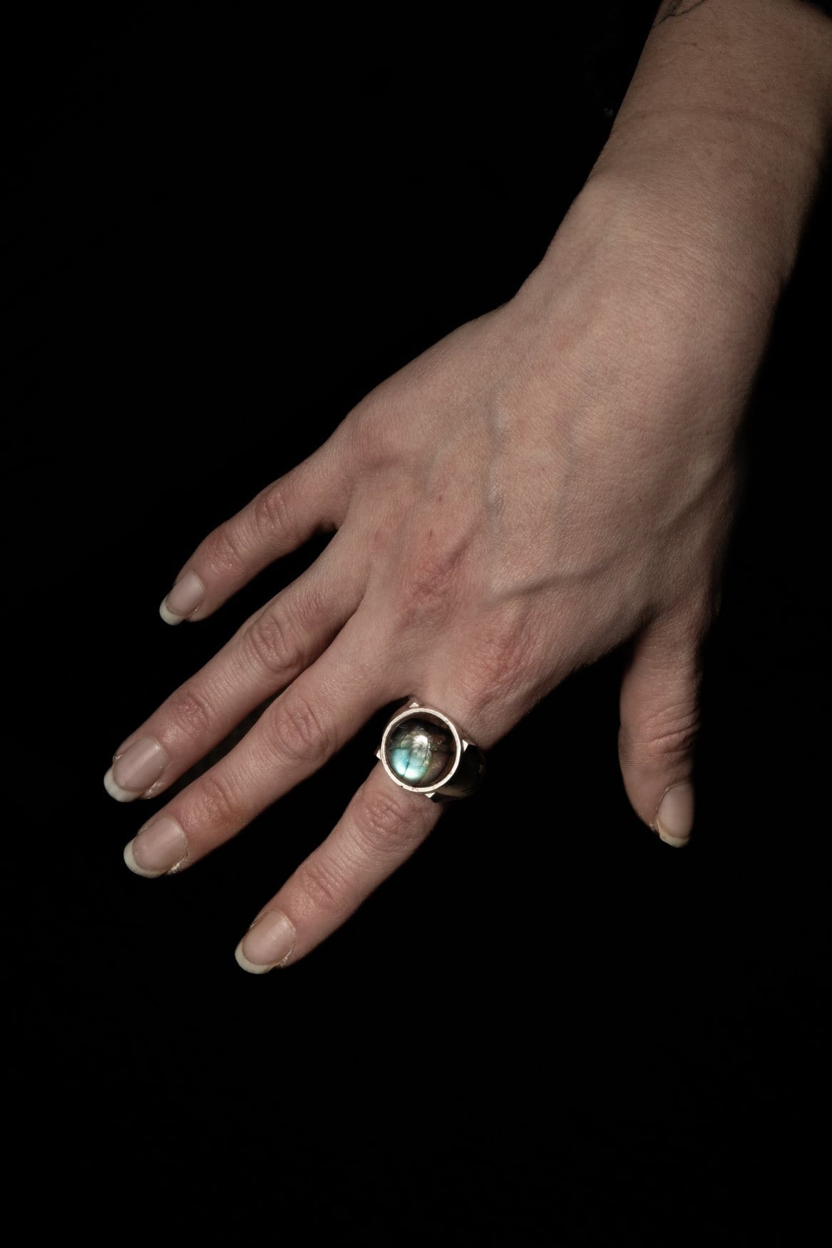 Bague labradorite portée, main sur fond noir
