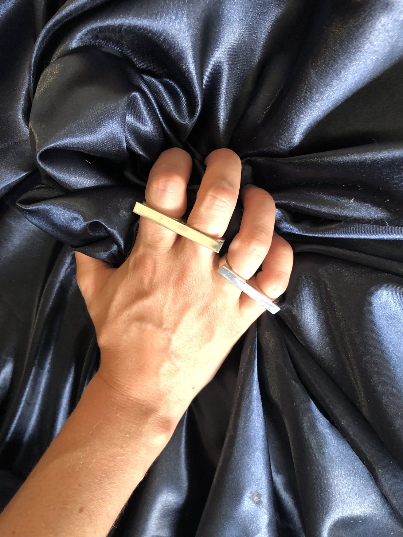 Main serrée dans du satin, bague en argent