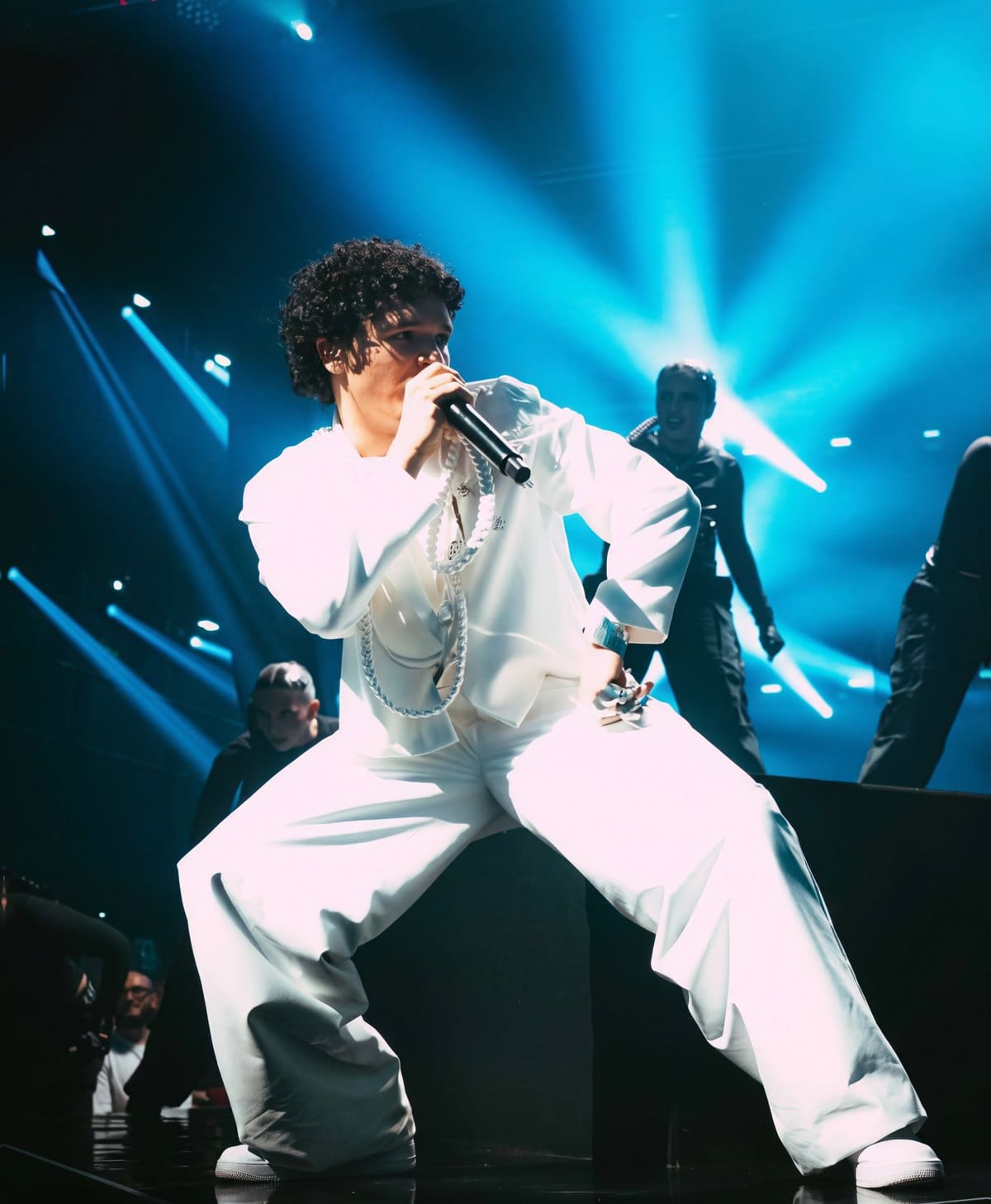 Chanteur sur scène en costume blanc, bijoux en argent